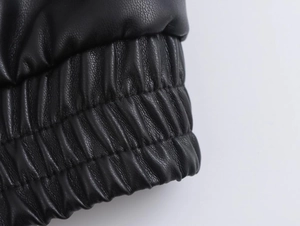 Close-up of black faux leather texture and elastic ribbed cuffs on a pilot jacket