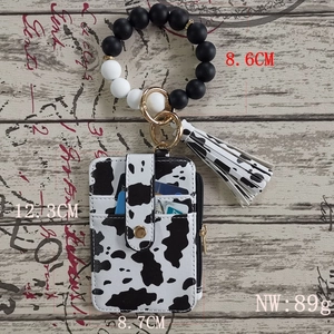 Detailed view of a cow print PU card wallet with silicone bead wristlet and tassel charm
