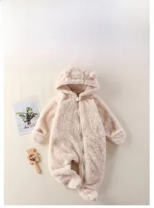 Flachbild von warmem cremefarbenem Baby-Fleece-Jumpsuit mit Tierohren und Holzrassel