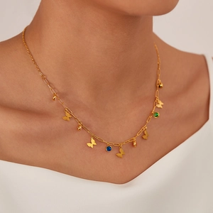 Close-up of gold butterfly necklace with colorful zircons worn by model on white top