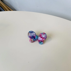 Detail of acetate butterfly hair clip with colorful marble pattern and small rhinestones