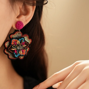 Close-up of colorful floral embroidery earrings with beads worn by a model