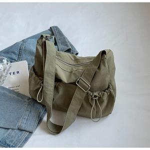 Detail of army green nylon hobo bag featuring functional side drawstring pockets