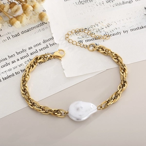 Detail of gold snake chain bracelet featuring a baroque pearl on aesthetic paper background