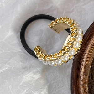 Macro shot of U-shaped alloy chain hair tie with white pearls on a minimalist background