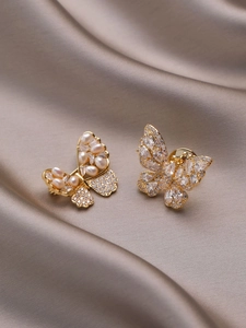 Detailed macro view of butterfly brooches with inlaid pearls and zircon on champagne silk