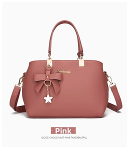 Detail of pink faux leather handbag featuring a bow charm and golden Dunkway logo