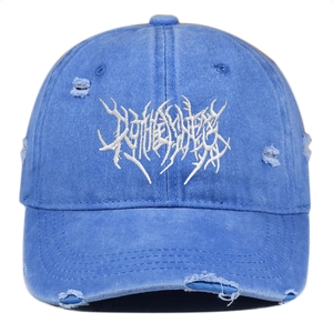 Close-up of blue distressed baseball cap with white gothic embroidery and ripped details