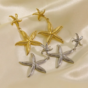 Golden and silver double starfish drop earrings with fine texture on silk background