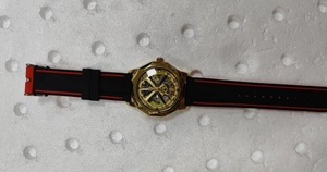 Détail de montre mécanique squelette avec boîtier doré et bracelet silicone noir rouge