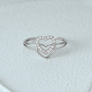 Macro view of double heart S925 sterling silver ring with pavé diamonds and open band