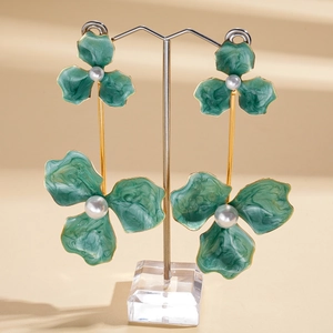 Detail view of vintage bohemian earrings with green enamel flowers and pearls