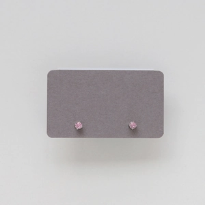 Macro shot of pink round-cut birthstone stud earrings in silver four-prong setting