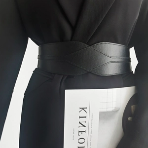 Detail of elegant black PU leather wide waist belt on a black suit jacket for women