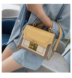 Close-up of tricolor stitching on a small crossbody bag with gold chain and woven details