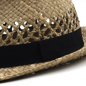 Dettaglio della trama di paglia intrecciata e nastro in gros-grain nero sul cappello
