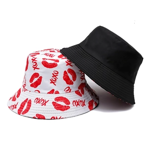 Detail view of double-sided bucket hats with red lip prints, XOXO text and plain black side
