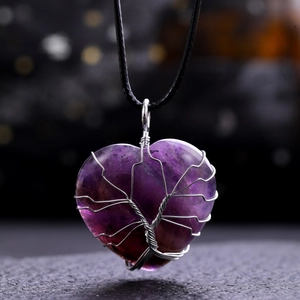 Detailed close-up of heart-shaped purple crystal pendant wrapped in silver tree wire design