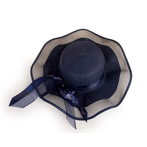 Detail of navy straw hat with mesh brim and silk ribbon featuring golden happy text