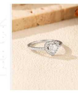 Macro shot of silver heart moissanite ring with pavé diamonds on textured stone surface