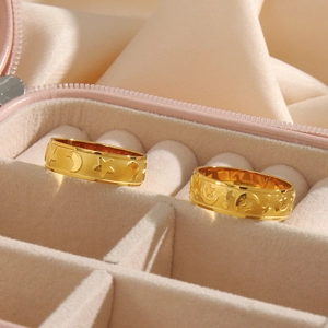 Close-up of golden star and moon embossed rings displayed in a pink velvet jewelry box