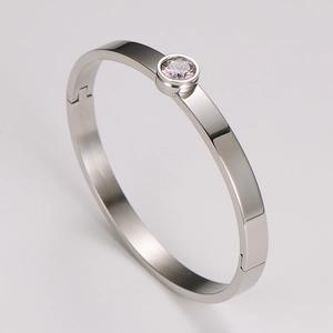 Macro detail of silver stainless steel bangle showing the single diamond setting and hinge