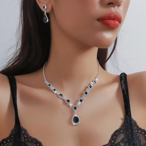 Macro detail of teardrop necklace and earrings set with black crystals on model