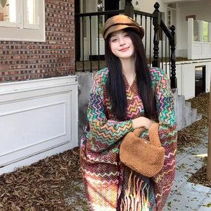 Ethnic knit shawl with colorful zigzag patterns and tassels worn in an autumn street setting