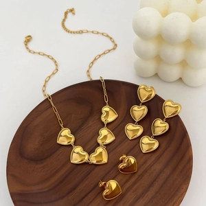 Parure de bijoux coeur dorée 18 carats avec bords perlés sur plateau en bois