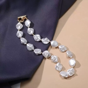 Detail of baroque pearl necklace with golden clasp on luxurious blue velvet background