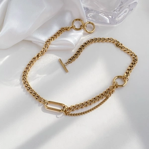 Detail of layered gold cuban and paperclip link necklace with elegant toggle clasp