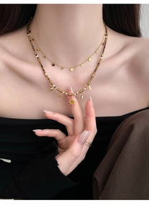Close-up of layered tiger eye beaded necklace with gold sun and star pendants
