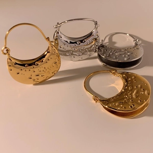 Detail of gold and silver textured crescent earrings with hammered metallic finish