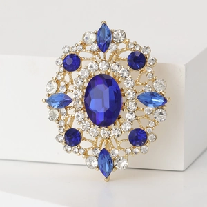 Detailed shot of retro oval blue crystal brooch with intricate gold floral metalwork