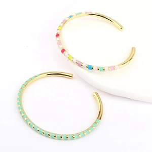 Detail of colorful enamel gold-plated open cuff bracelets with bohemian spiral texture