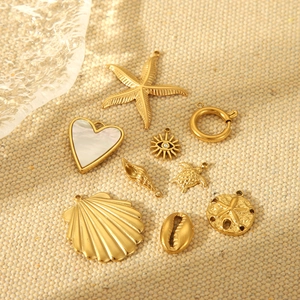 Macro view of gold stainless steel ocean charms with seashell, heart and sea turtle motifs