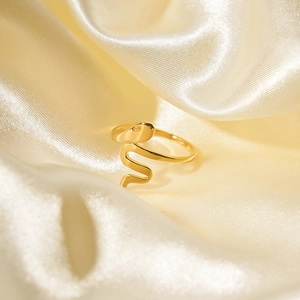 Elegante anello a serpente in oro rosa con texture lucida su seta gialla