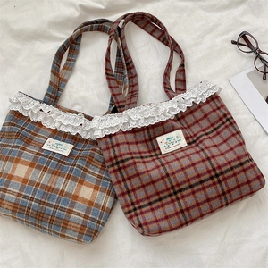 Close-up of vintage plaid tote bags featuring delicate white lace trim and Happy patch