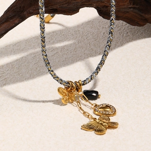 Dettaglio di ciondoli a farfalla e cuore in oro 18K su una catena intrecciata a mano
