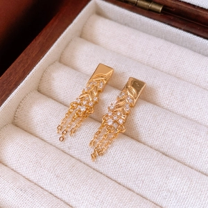 Detail of 18K gold plated tassel earrings with sparkling crystals in a beige jewelry box