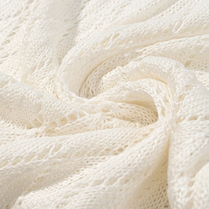 Macro-opname van witte opengewerkte gebreide stof met delicate mesh-structuur en zachte afwerking
