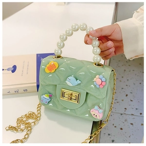 Close-up of green jelly purse for girls with pearl handle and golden chain strap