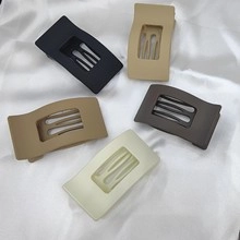 Detailed view of five matte rectangular hair clips in neutral tones on white silk fabric