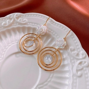 Détail de boucles d'oreilles rose avec anneaux dorés et cristaux sur céramique