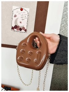 Detail view of brown PVC jelly bag with cheese pattern texture and metal chain strap
