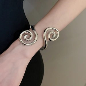 Close-up of a silver spiral cuff bracelet on a model's wrist with polished mirror finish