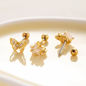 Macro view of gold titanium steel ear studs set with butterfly, star and crown designs