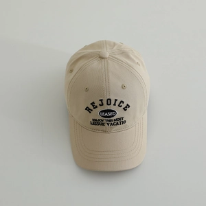 Close-up of beige cotton baseball cap featuring black embroidered letters and top eyelets
