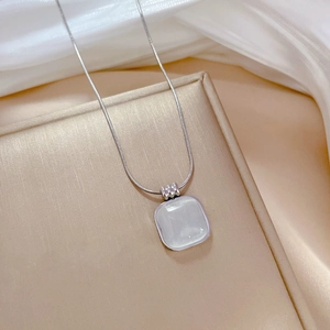 Close-up of square cat eye stone pendant on a silver snake chain over a gift box