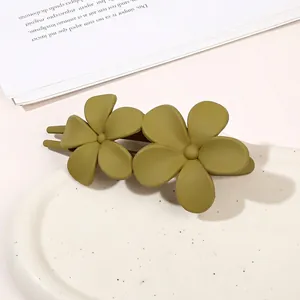 Close-up of matte olive green double flower hair claw clip on a ceramic tray
